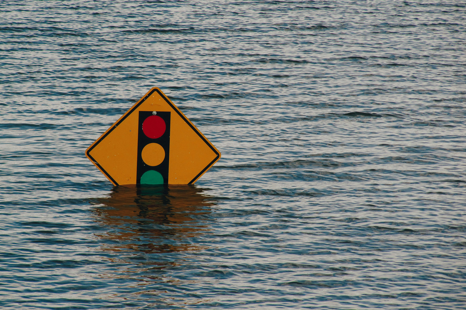 The top of a yellow traffic light sign sticking out above a flooded area