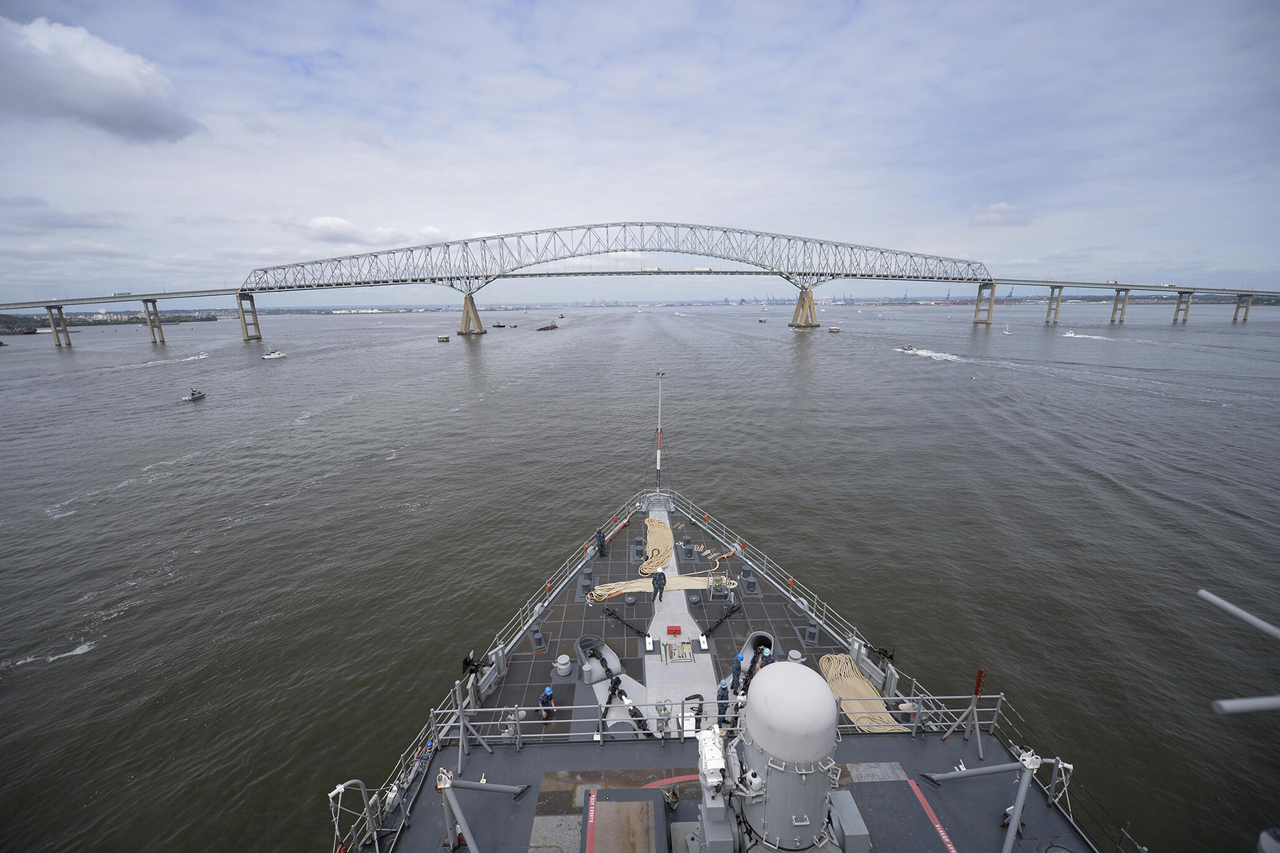 the front of a ship on the water with clear skies and the Key Bridge across the horizon