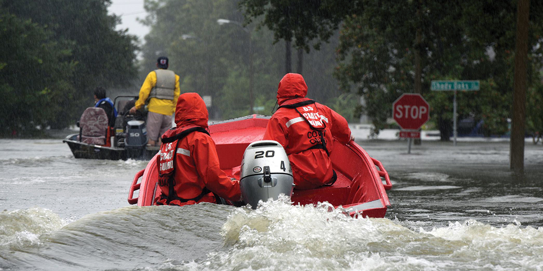 Coast Guardsmen in an inflatable motor boat motoring down a flooded street